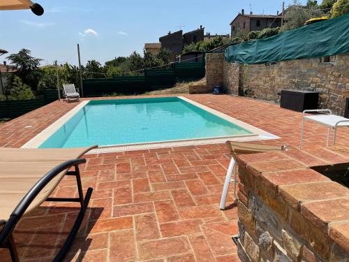 a swimming pool on a brick patio with two chairs at Casa Bici in Chianni