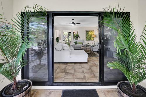 a living room with a white couch and palm trees at Villa Blue - Coastal Family Escape in Palm Cove