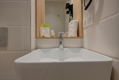 a white sink in a bathroom with a mirror at Brit Hotel Europ Bergerac in Bergerac