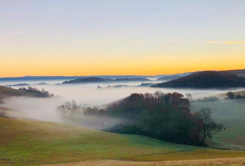 a foggy hillside with a field and trees in the foreground at les gîtes d'en Julio in Puylaurens