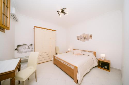 a white bedroom with a bed and a desk and a table at Rosemary Holiday House in Conca dei Marini