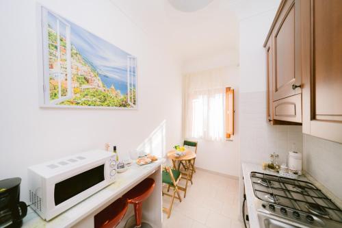 a white kitchen with a microwave and a table at Rosemary Holiday House in Conca dei Marini