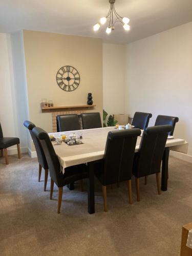 a dining room with a table and chairs and a clock at Dunelm House in Seahouses