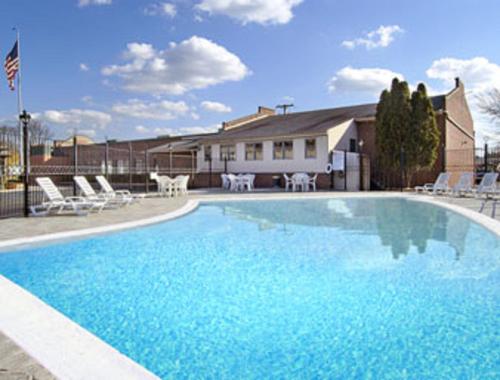 a large blue swimming pool with chairs and a house at Aderi Hotel Near Bucknell University in Lewisburg