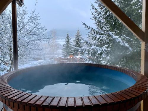 a hot tub in a room with snow on the ground at Pensiunea Hétvezér Panzió in Sub Cetate