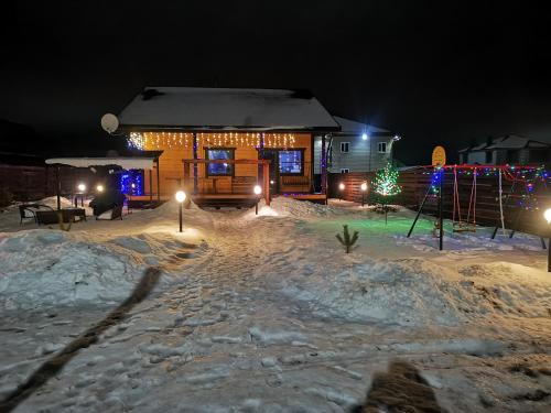 a house with christmas lights in the snow at night at Коттедж "Веселый апельсин" in Yeksolovo