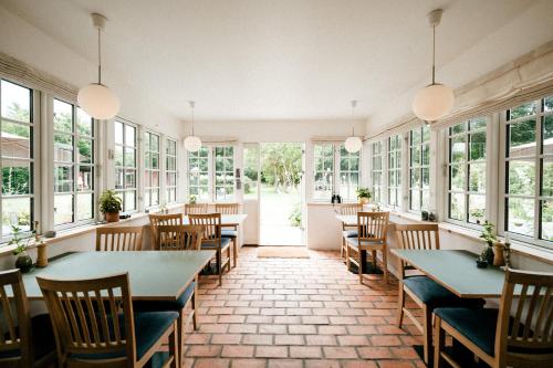 a restaurant with tables and chairs and windows at Langebjerg Pension & Spisested in Allinge