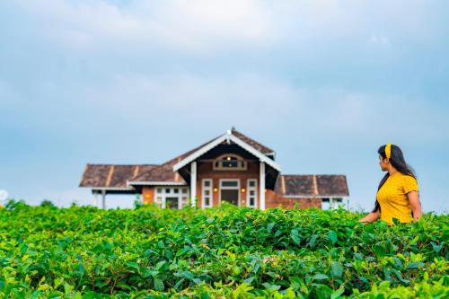 a woman sitting in a field in front of a house at Zostel Homes Wayanad (Vythiri) in Wayanad