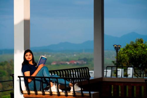 a woman sitting on a bench reading a book at Zostel Homes Wayanad (Vythiri) in Wayanad