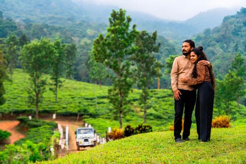 a man and a woman standing on top of a hill at Zostel Homes Wayanad (Vythiri) in Wayanad