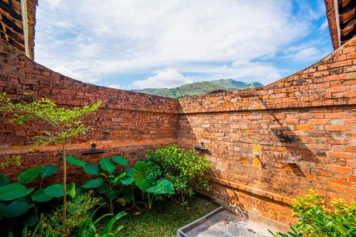 a brick wall with a pond in a garden at Zostel Homes Wayanad (Vythiri) in Wayanad