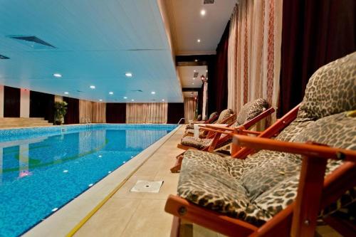 een zwembad in een hotel met stoelen ernaast bij Гранд Манастира Частен Апартамент in Pamporovo