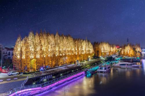 a city lit up at night next to a river at Huzhou Wealth Hotel in Huzhou