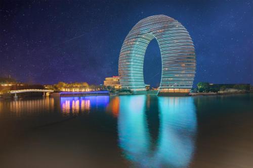 a building with a reflection in the water at night at Huzhou Wealth Hotel in Huzhou
