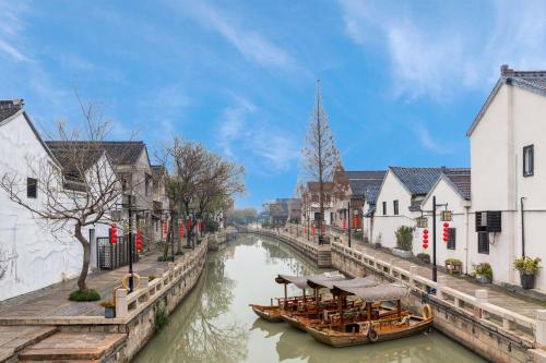 a river with two boats in a city with buildings at Huzhou Wealth Hotel in Huzhou