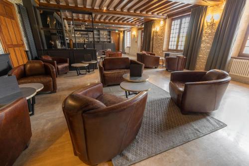 a lobby with leather chairs and tables and a bar at Ferme de la Rançonnière - Hôtel & Restaurant in Crépon