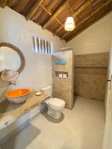 a bathroom with a toilet and a sink and a mirror at Vilarejo Macapá Chalés in Luis Correia
