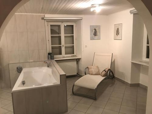 uma casa de banho com uma banheira e uma cadeira. em le gîte de la Tourette em Hohrod