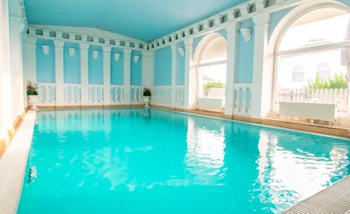 einen Innenpool mit blauem Wasser in einem Zimmer mit Fenstern in der Unterkunft Styria hotel Chvalovice in Znojmo