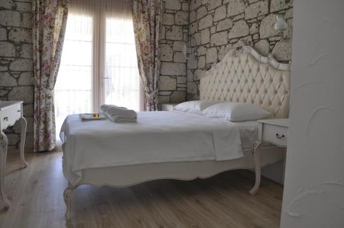 a bedroom with a white bed and a stone wall at Alacati Lucky Angel Hotel in Alaçatı