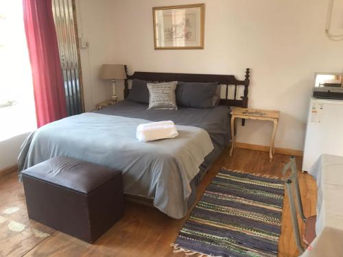 a bedroom with a large bed with a ottoman and a table at Serenity Guesthouse in Klerksdorp