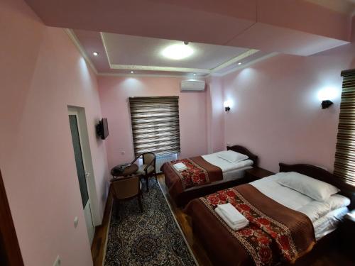 two beds in a room with pink walls at VOSTOK in Samarkand