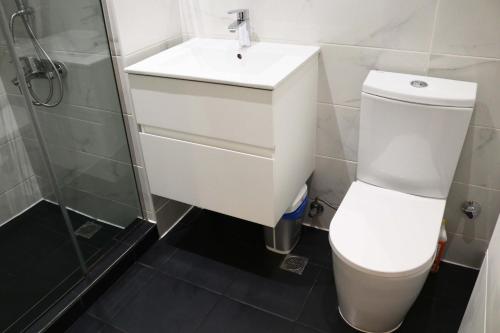 a bathroom with a white toilet and a sink at APARTMENTS GH - Accra - Cantonments - Embassy Gardens in Accra