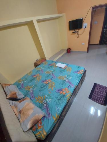 a bed in a room with a blue comforter at Alpine Green in Rānchī
