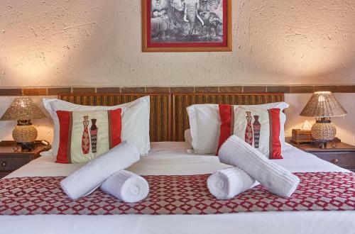 a bed with two pillows and two towels on it at Grand Kruger Lodge and Spa in Marloth Park