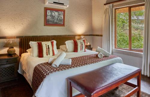 a bedroom with two beds and a window at Grand Kruger Lodge and Spa in Marloth Park