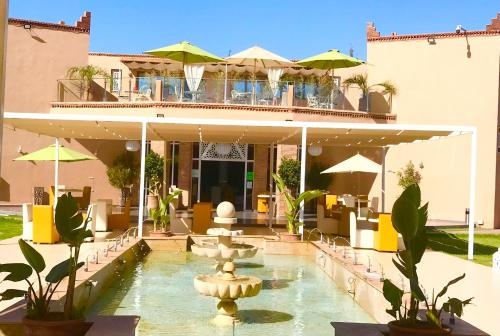a hotel with a fountain in front of a building at Villa Kesh Evasion Marrakech in Marrakech