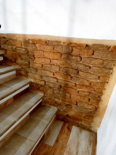 an empty room with a brick wall and stairs at B&B Santu Giuvanni "Un tuffo nel passato Fonnese" in Fonni