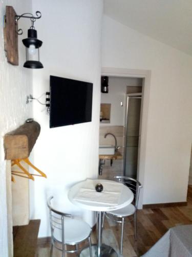 a living room with a table and a tv on a wall at B&B Santu Giuvanni "Un tuffo nel passato Fonnese" in Fonni