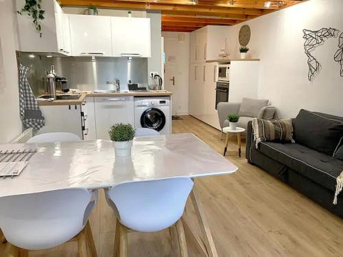 een keuken en een woonkamer met een witte tafel en stoelen bij Cottage T3 à 5 minutes à pied de la plage in Le Pouliguen