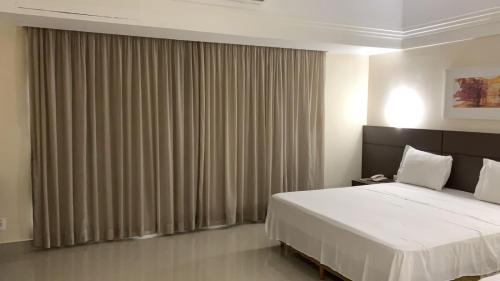 1 dormitorio con 1 cama y una ventana grande con cortinas en Tropical Executive Hotel flat, en Manaus