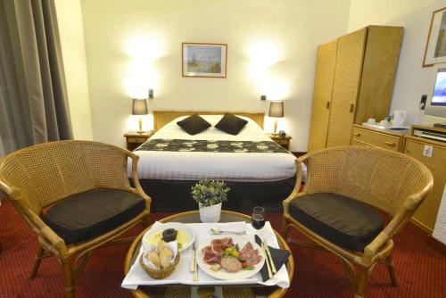 a hotel room with a bed and two chairs and a tray of food at Hôtel d’Angleterre Grenoble Hyper-Centre in Grenoble