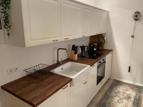 kuchnia z białymi szafkami i zlewem w obiekcie Grimming Appartement Schladming w mieście Sonnberg