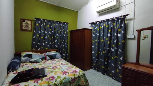 een slaapkamer met een bed met blauwe en gele gordijnen bij Homestay Opah Parit Buntar, Perak in Parit Buntar