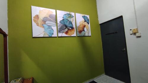 four pictures on a green wall in a room at Homestay Opah Parit Buntar, Perak in Parit Buntar