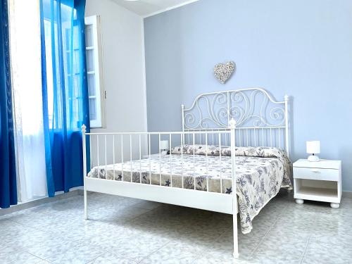 a white bed in a bedroom with a blue wall at Villa Azzurra in Marina di Mancaversa