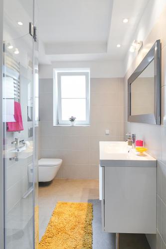a bathroom with a sink and a toilet and a mirror at Costa Apartments in Sopot