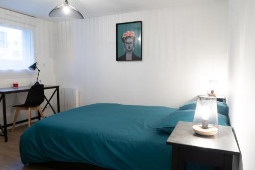 1 dormitorio con cama azul y escritorio con lámpara en Bel appartement idéalement placé Saint-Brieuc, wifi, parking gratuit en Saint-Brieuc