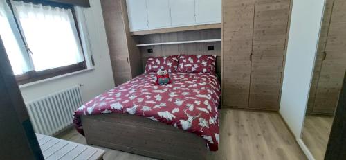 a small bed with a red comforter in a room at Genzianella in Tarvisio