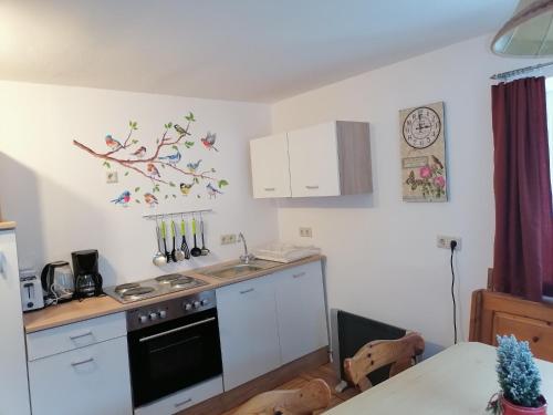 una cucina con armadi bianchi e un tavolo con un albero sul muro di Ferienwohnung Riedbach a Innsbruck