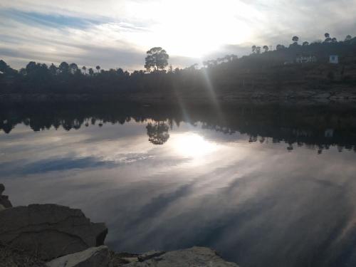 a reflection of the sun on a lake at Ritu Raj Home Stay & Cafe in Malther
