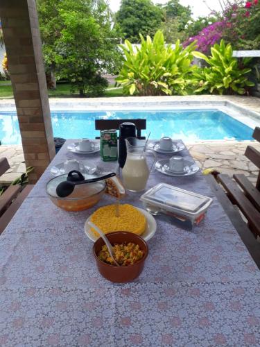 Refúgio das bouganvillea في Igarassu: طاولة عليها طعام بجوار حمام سباحة