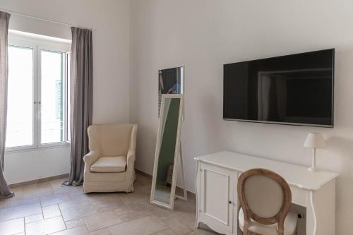 a living room with a chair and a television on the wall at Albergo Diffuso Monopoli in Monopoli