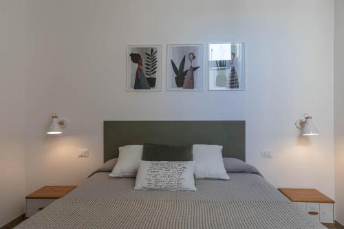 a bedroom with a bed with three pictures on the wall at Albergo Diffuso Monopoli in Monopoli