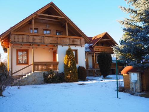 a wooden house with a balcony in the snow at Privat Alenka in Liptovský Mikuláš
