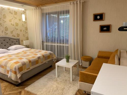 a bedroom with a bed and a couch and a window at Sadyba Anastasia in Slavske